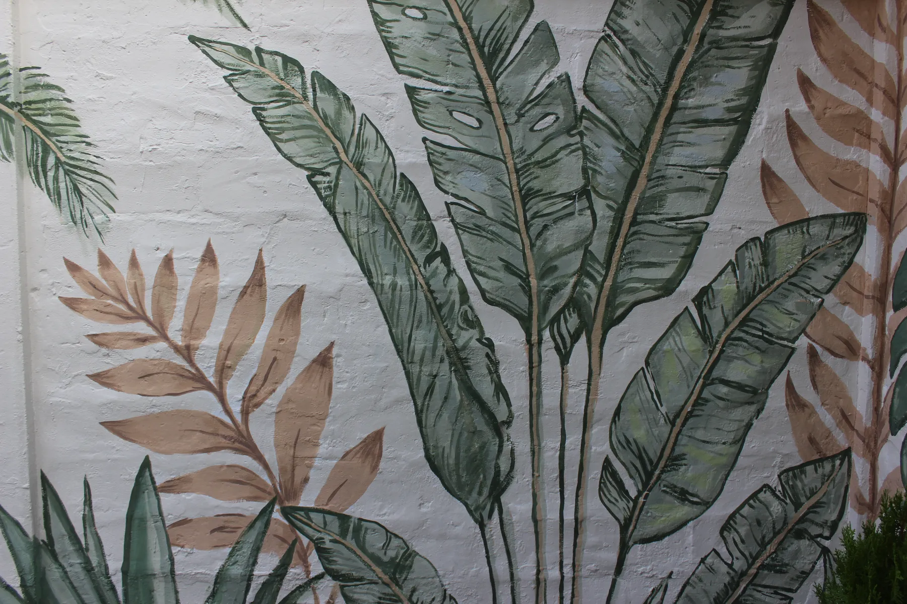Detail of hand-painted large leaves on the backyard wall