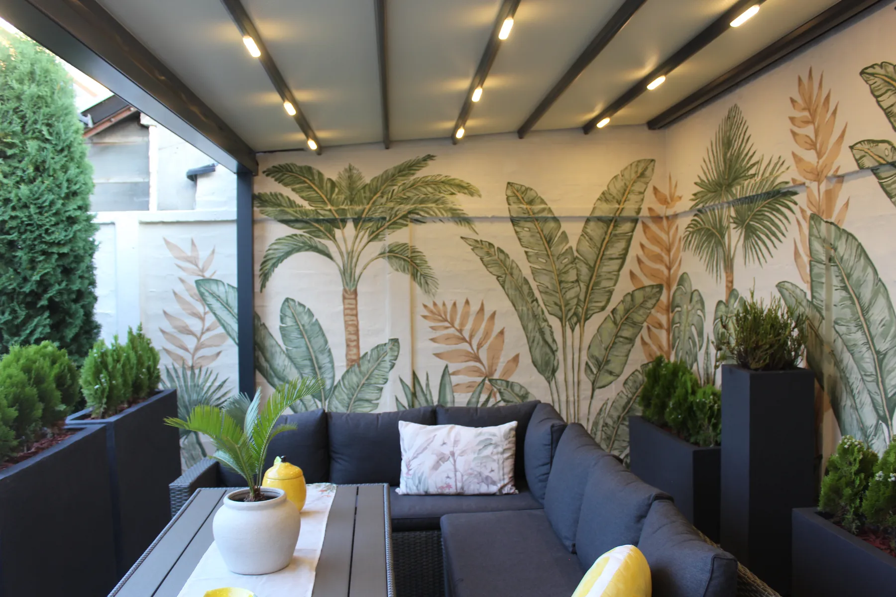 Backyard mural with tropical plants behind an outdoor seating area